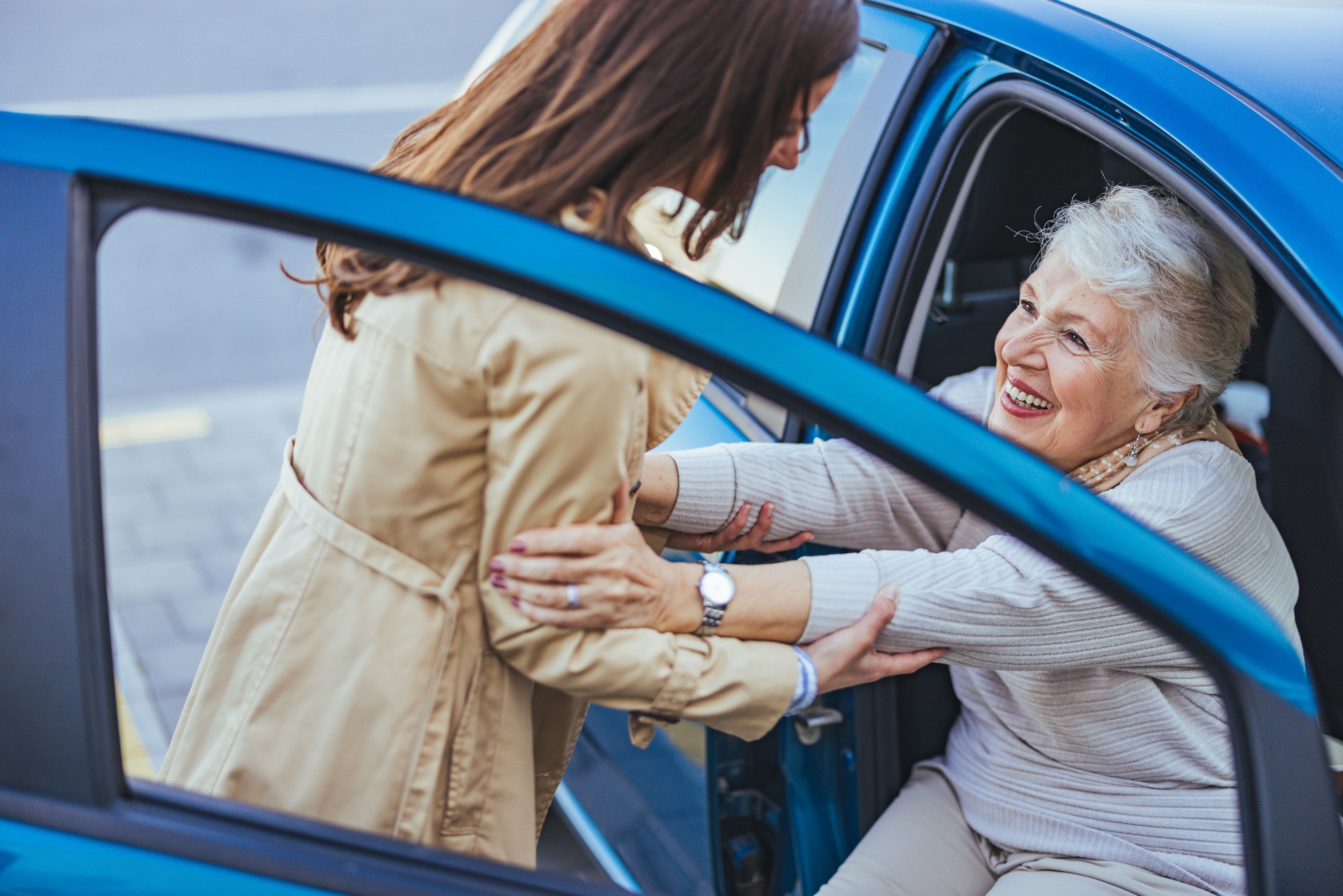 Smiling Elderly Woman Being Assisted Out of a Car
